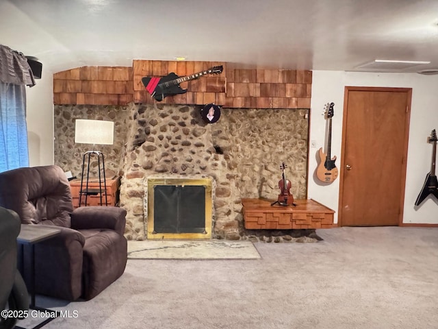 living room featuring vaulted ceiling, carpet flooring, and a stone fireplace