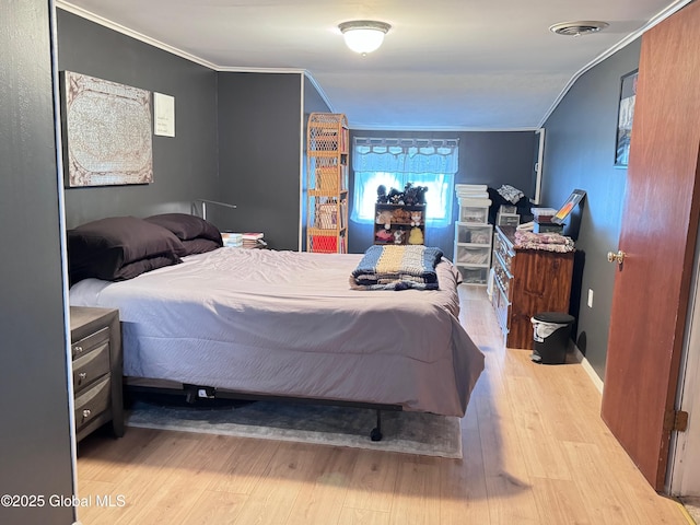 bedroom with ornamental molding, visible vents, and wood finished floors