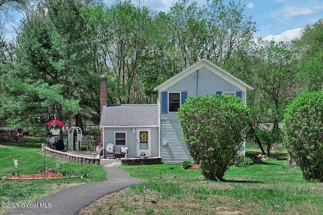 view of front facade featuring a patio area, a chimney, and a front yard