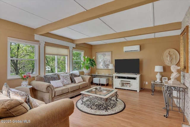 living area featuring beamed ceiling, light wood-style flooring, and an AC wall unit