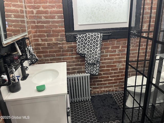 bathroom featuring brick wall, vanity, and radiator heating unit
