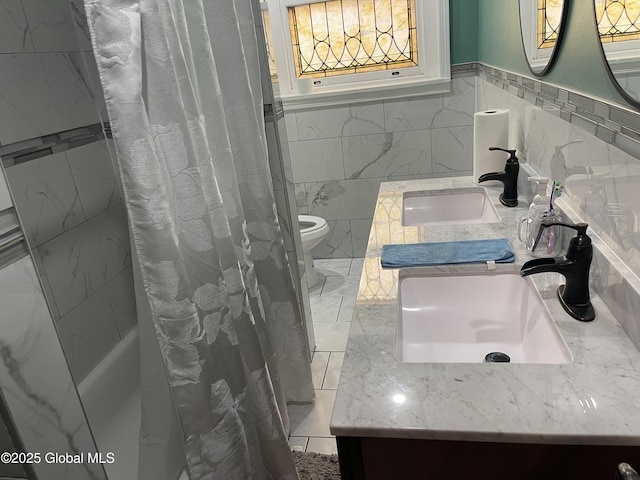 bathroom featuring a wainscoted wall, vanity, toilet, and tile walls
