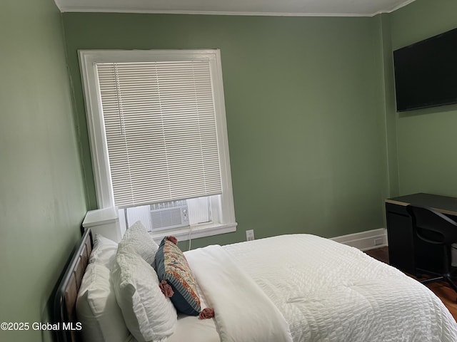 bedroom featuring baseboards, crown molding, and wood finished floors