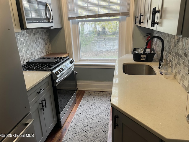 kitchen with backsplash, stainless steel appliances, dark wood-style floors, and a sink