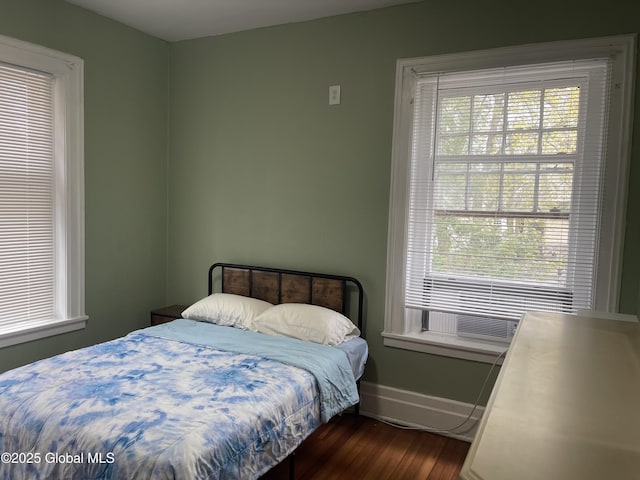 bedroom with baseboards, dark wood-style floors, and multiple windows