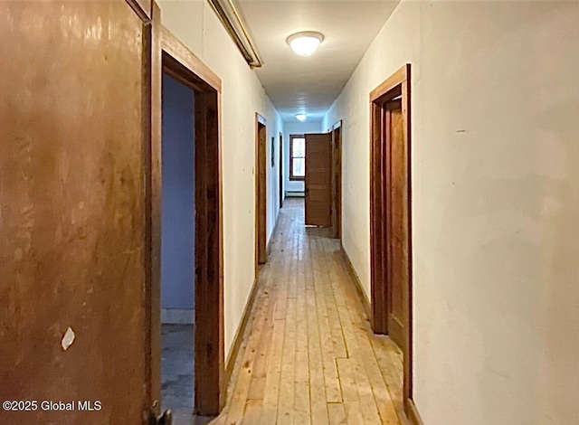 corridor featuring light wood-type flooring and baseboards