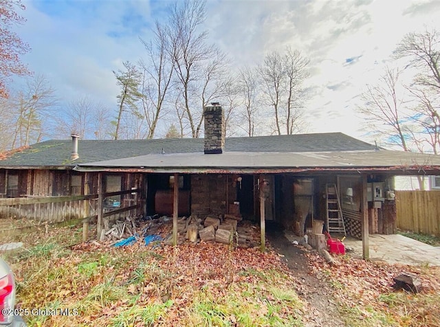 back of house featuring a chimney and fence