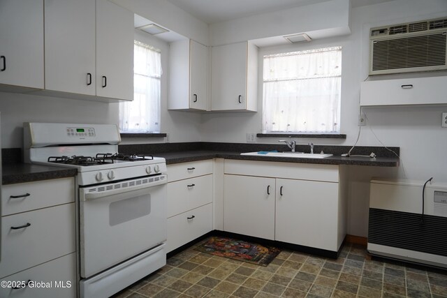 6222 Rte 9n, Hadley, NY 12835 - kitchen with white gas stove, a sink, dark countertops, and white cabinetry