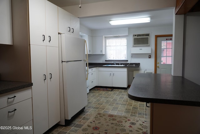 6222 Rte 9n, Hadley, NY 12835 - kitchen with freestanding refrigerator, dark countertops, an AC wall unit, a sink, and white cabinetry