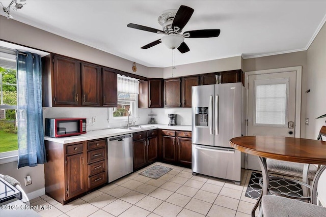 kitchen featuring stainless steel appliances, a sink, light countertops, light tile patterned flooring, and ornamental molding