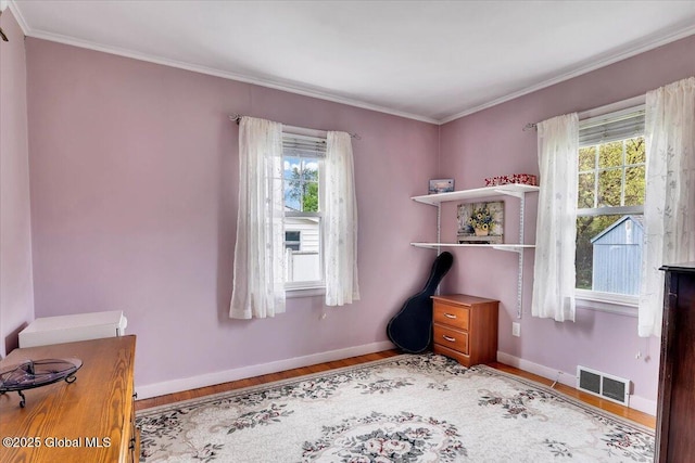 bedroom featuring wood finished floors, ornamental molding, and baseboards