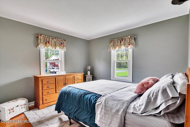 bedroom featuring crown molding, light wood-type flooring, and baseboards