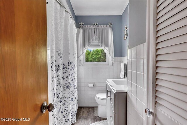 full bathroom featuring tile walls, toilet, wood finished floors, vanity, and crown molding