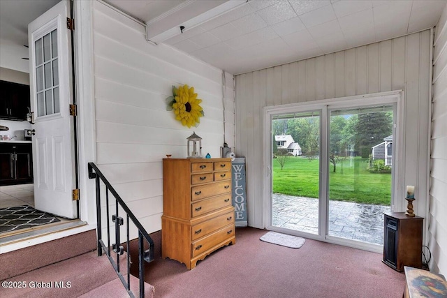 doorway featuring carpet and wood walls