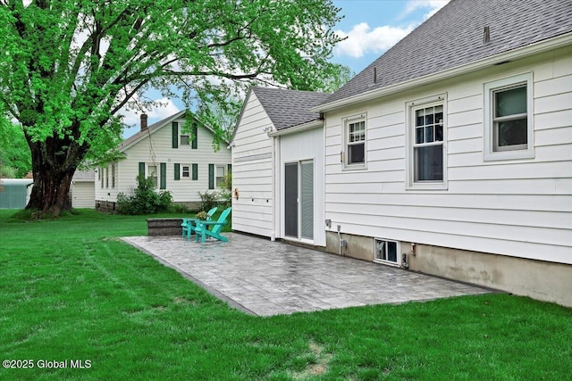 rear view of house with a yard, a patio area, and roof with shingles