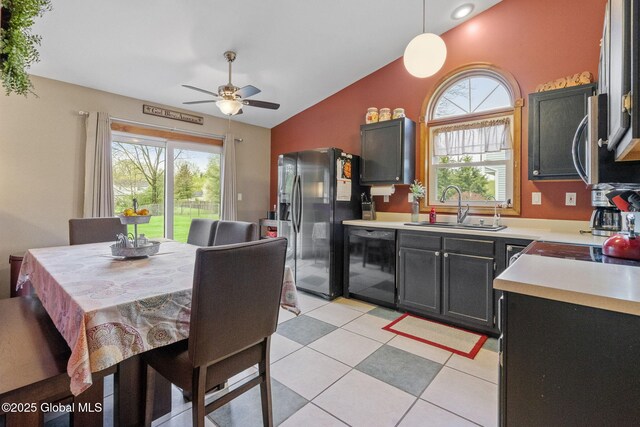 kitchen with a sink, stainless steel appliances, lofted ceiling, light countertops, and a ceiling fan