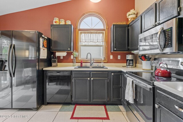 kitchen with stainless steel appliances, a sink, light countertops, vaulted ceiling, and light tile patterned floors