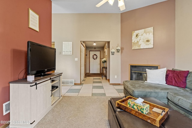living area featuring ceiling fan, light tile patterned floors, baseboards, and a multi sided fireplace
