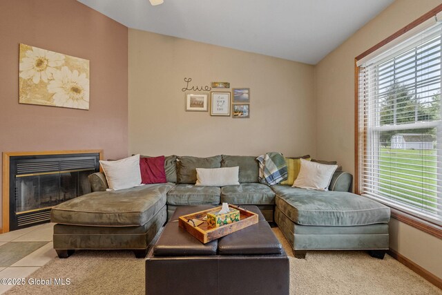 living room featuring lofted ceiling, healthy amount of natural light, a fireplace with flush hearth, and baseboards
