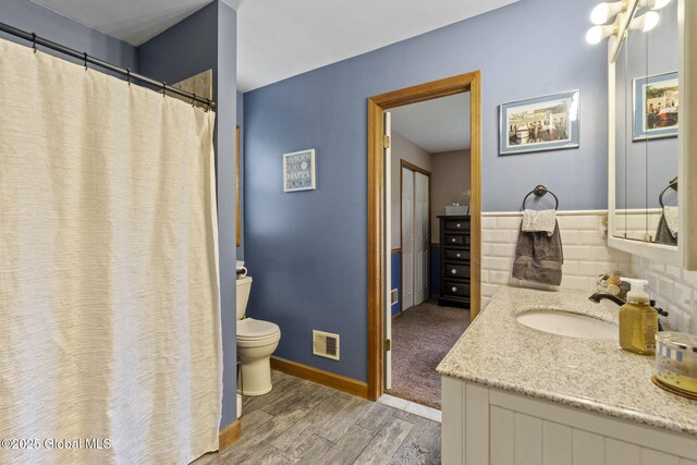 full bathroom with wood finished floors, toilet, vanity, and baseboards