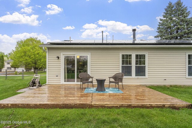 rear view of house with a deck and roof mounted solar panels