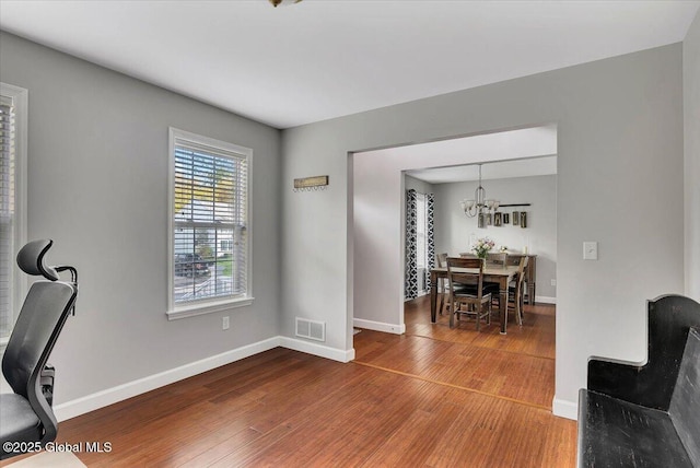 office with wood-type flooring, a chandelier, and baseboards