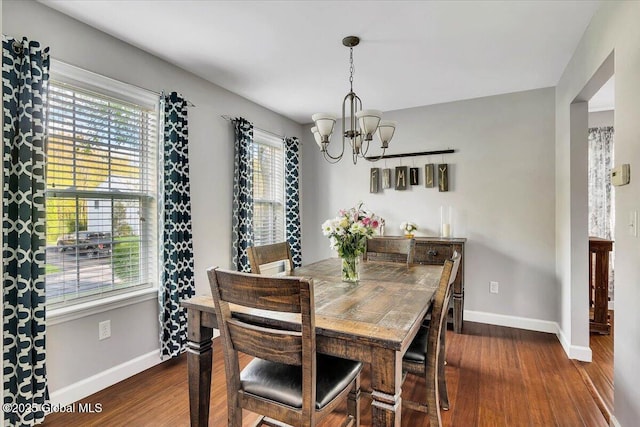 dining room with a chandelier, dark wood-type flooring, and baseboards