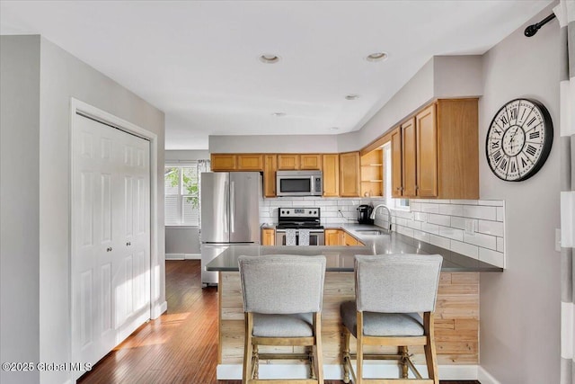 kitchen featuring appliances with stainless steel finishes, a sink, backsplash, open shelves, and baseboards