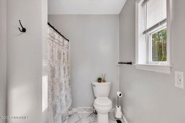 full bath featuring baseboards, marble finish flooring, toilet, and curtained shower