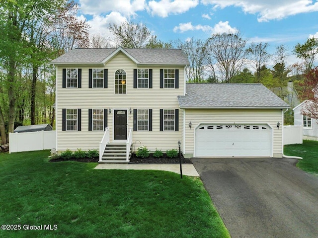colonial inspired home with asphalt driveway, a garage, and roof with shingles