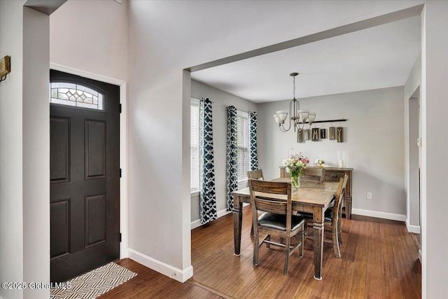 entrance foyer with a chandelier, baseboards, and dark wood finished floors