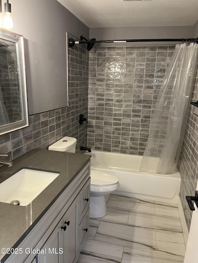 full bathroom with toilet, tile walls, vanity, and shower / bath combo with shower curtain