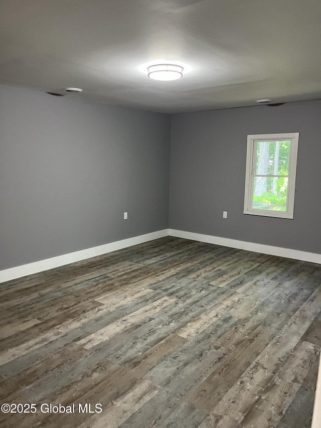 empty room featuring baseboards and dark wood finished floors