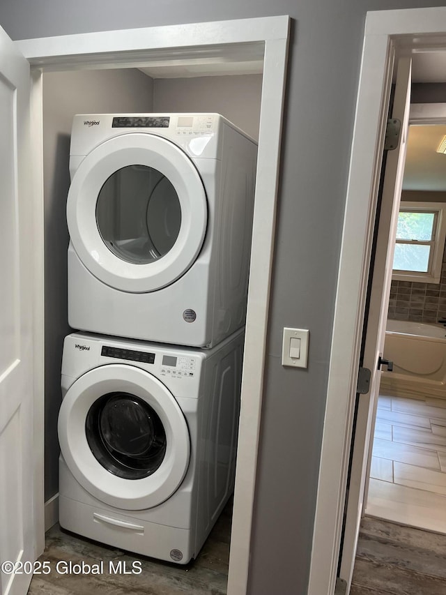 washroom with laundry area, stacked washer and clothes dryer, and wood finished floors
