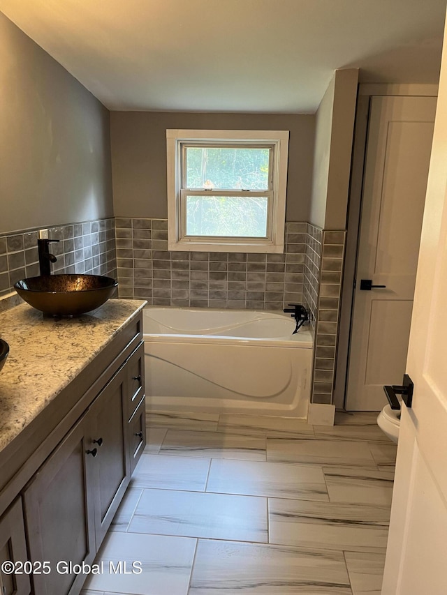 bathroom with tile walls, tile patterned floors, vanity, and a bath