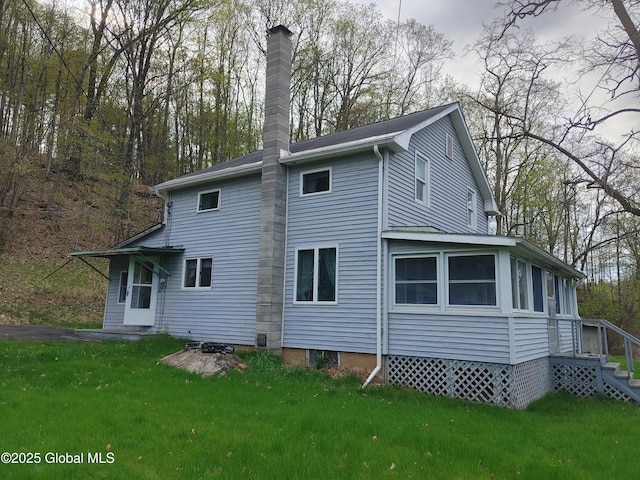 rear view of house with a chimney and a lawn