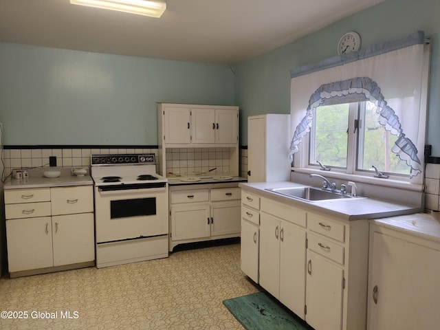 kitchen with decorative backsplash, white cabinets, electric stove, and a sink