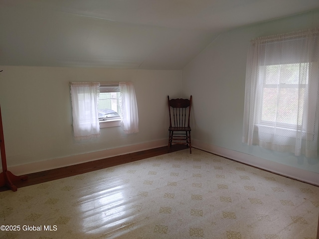 additional living space featuring baseboards, wood finished floors, and vaulted ceiling