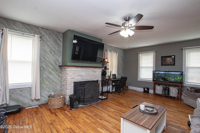 living room with a wealth of natural light, a fireplace, and ceiling fan