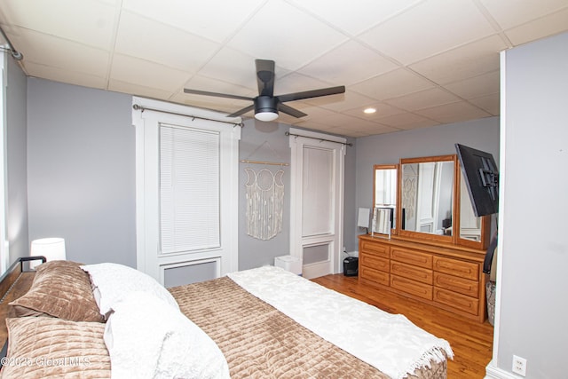 bedroom featuring a drop ceiling, wood finished floors, a ceiling fan, and recessed lighting