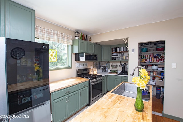 kitchen with refrigerator, open shelves, green cabinetry, stainless steel range with gas cooktop, and butcher block counters