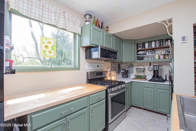 kitchen with wood counters, open shelves, appliances with stainless steel finishes, and green cabinets
