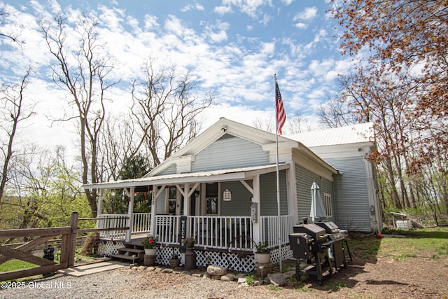 farmhouse inspired home featuring a porch and metal roof