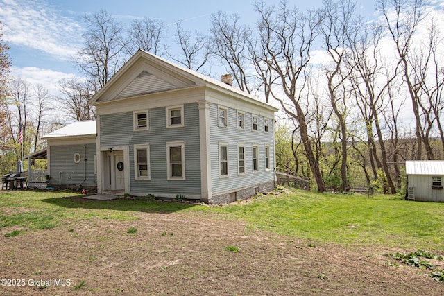 view of front of house with a front lawn, a storage shed, an outbuilding, and a chimney