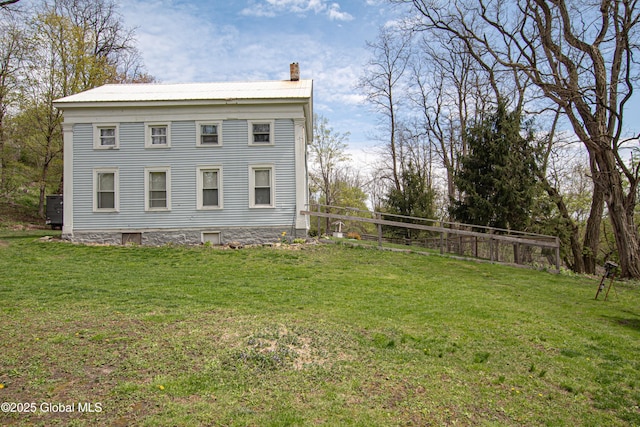 view of property exterior with a chimney, fence, and a lawn