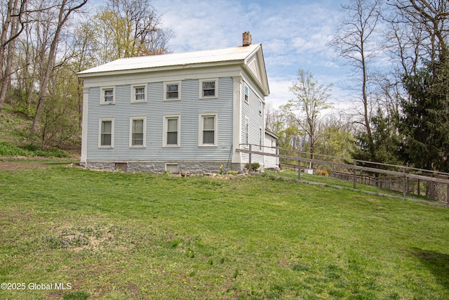 view of side of property featuring a chimney, a yard, and fence