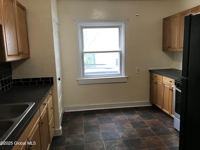 23 Orville St, Glens Falls, NY 12801 - kitchen with dark countertops, baseboards, a sink, freestanding refrigerator, and brown cabinetry