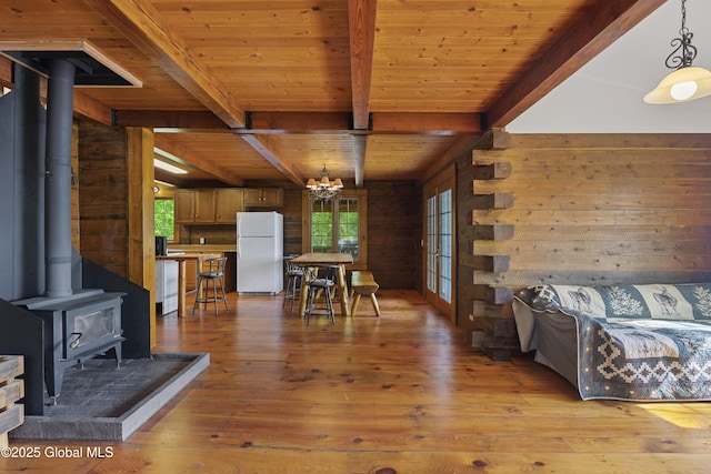 89 Captains Cv, Crown Point, NY 12928 - living area with a wood stove, wood walls, a chandelier, light wood-style flooring, and beamed ceiling