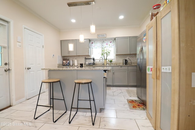 kitchen featuring gray cabinetry, backsplash, a kitchen breakfast bar, light marble finish floors, and ornamental molding