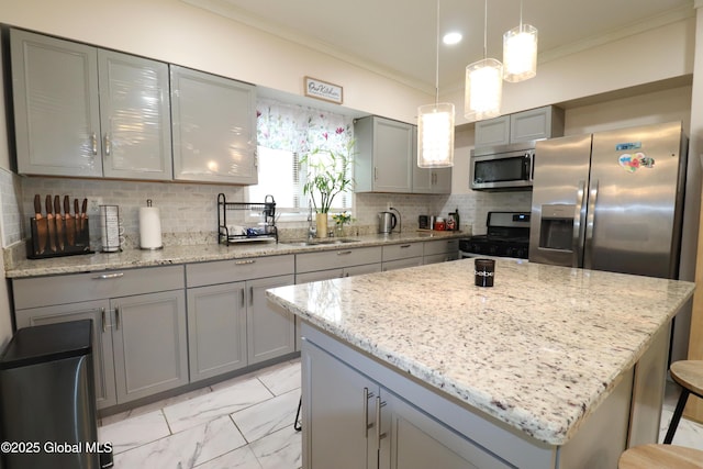 kitchen featuring stainless steel appliances, gray cabinets, crown molding, a kitchen island, and light stone countertops